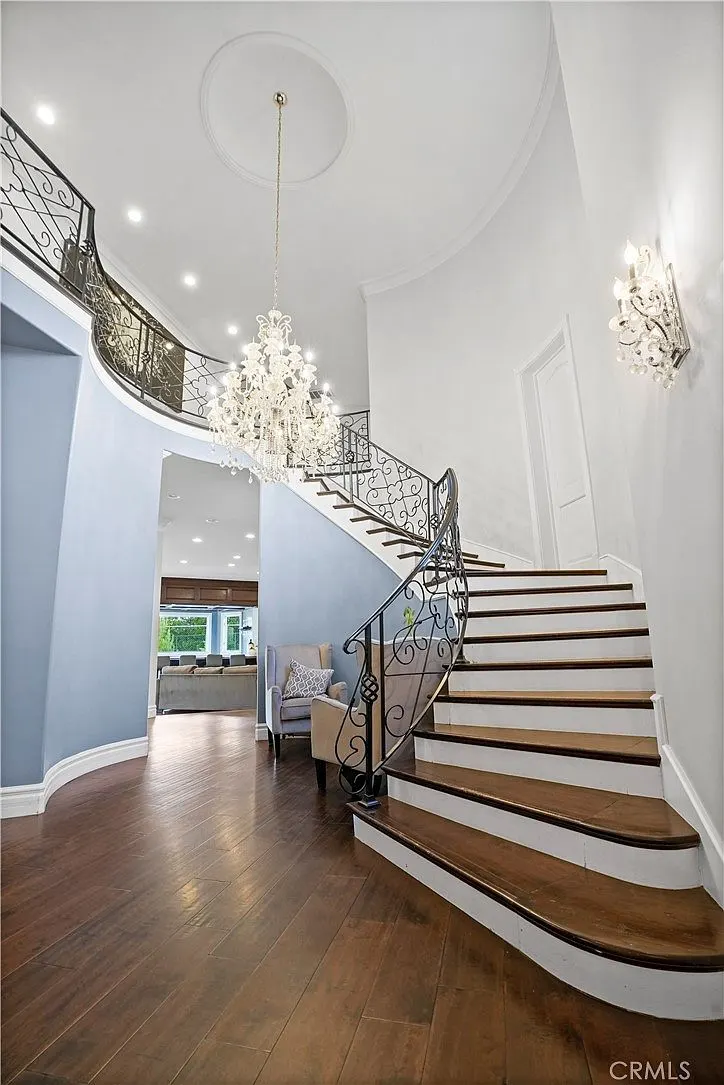 Curved staircase and chandelier from the landing at One Zoom Listing